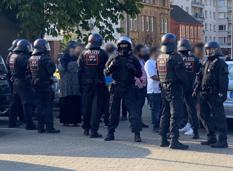 Polizisten stehen bei einer Massenschlägerei und schirmen eine Gruppe von Personen ab. Bei der Massenschlägerei zwischen zwei größeren Gruppen sind am Donnerstagabend in Castrop-Rauxel mehrere Menschen schwer verletzt worden. Es gebe darunter auch eine lebensgefährlich verletzte Person, sagte ein Polizeisprecher. Der Einsatz laufe aber noch. Die Polizei war mit starken Kräften vor Ort.