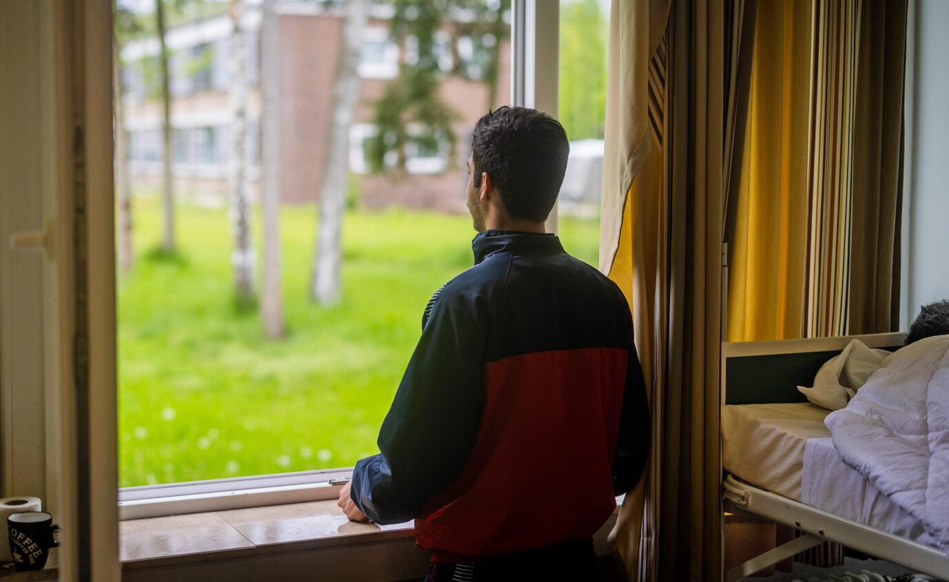 Ein junger Mann aus Syrien blickt aus dem Fenster seiner Unterkunft in der Erstaufnahmeeinrichtung fuer Gefluechtete in Bramsche-Hesepe in Niedersachen bei Osnabrueck und will wie andere Asylanträge stellen.