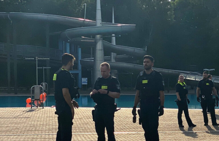 Polizisten stehen nach der Räumung im Sommerbad Neukölln am Columbiadamm. Freibäder sind keine gefährlichen Orte, darin besteht Einigkeit. Trotzdem muss ab und zu die Polizei eingreifen, weil junge Männer sich schlagen oder den Sprungturm stürmen. Die Bäder haben immer mehr Sicherheitsaufwand - und manche Besucher ein mulmiges Gefühl.