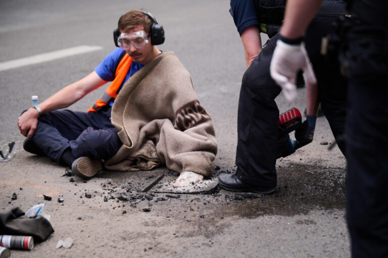 Ein Mitglied der "Letzten Generation" hat sich auf die Berliner Friedrichsstraße festgeklebt und wird von der Berliner Polizei aus dem Asphalt geschnitten Foto: picture alliance/dpa | Annette Riedl