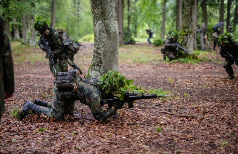 Reservisten der Bundeswehr stürmen während einer Übung durch ein Waldstück.