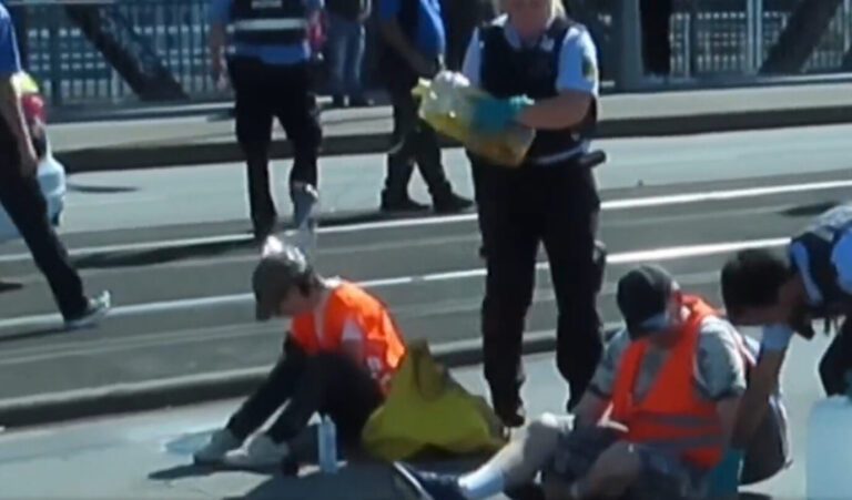 Der Moment, als die Polizistin dem Klimakleber in Mannheim einen Schluck Öl über den Kopf schüttet.