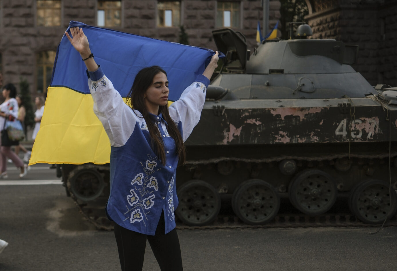 Eine Frau in Kiew hält eine Ukraine-Flagge, im Hintergrund steht ein erbeuteter russischer Panzer: Trotz des jüngsten Erfolgs wäre Euphorie verfrüht.