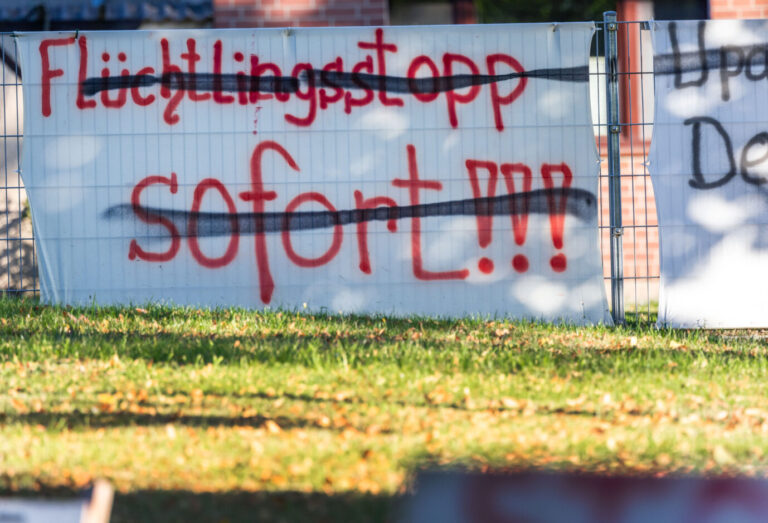 Ein Protestschild mit der durchgestrichenen Aufschrift „Flüchtlingsstopp sofort“ steht an der Ortsdurchfahrt. Die Umfragen zeigen: Die Mehrheit der Deutschen sieht die Integration weiterer Asylbewerber skeptisch. (Titelbild/Symbolbild)