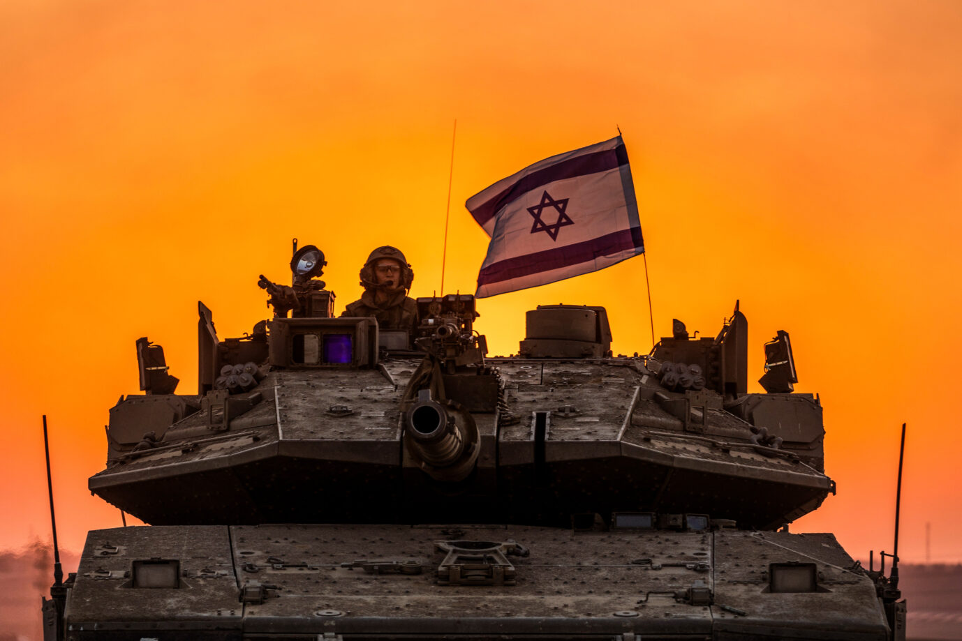 Israelischer Panzer mit israelischer Flagga fährt am Gaza-Streifen auf