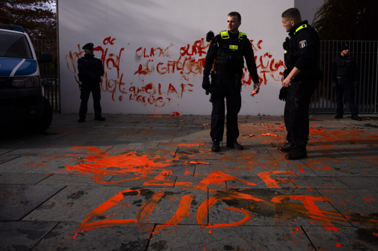 Auf dem Foto befinden sich drei Polizisten, die den Tatort einer Farbattacke der Vereinigung namens "Letzte Generation" erforschen. (Themenbild)
