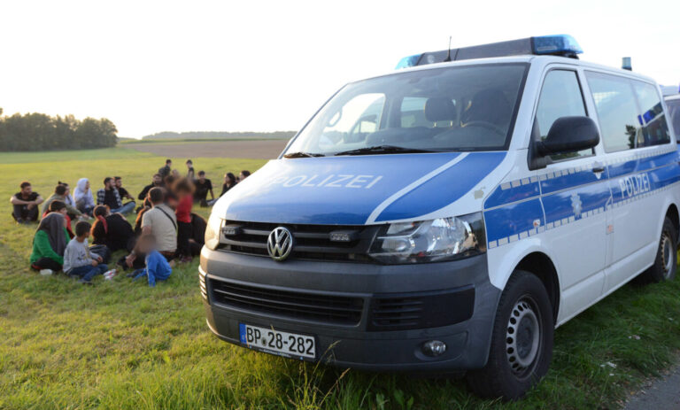 Eine Gruppe von Migranten aus Syrien und der Türkei sitzt neben einem Einsatzfahrzeug der Polizei. Die Bundespolizei in Sachsen hat erneut illegal eingereiste Geflüchtete entdeckt. Die 49 Menschen, darunter 20 Kinder, waren wohl mehrere Stunden bei hohen Außentemperaturen in einem Transporter eingesperrt, wie ein Sprecher der Bundespolizeiinspektion Ebersbach mitteilte. (zu dpa: «Bundespolizei findet Geflüchtete in Transporter - 20 Kinder darunter») Schleuser festgenommen. Ukrainer festgenommen.