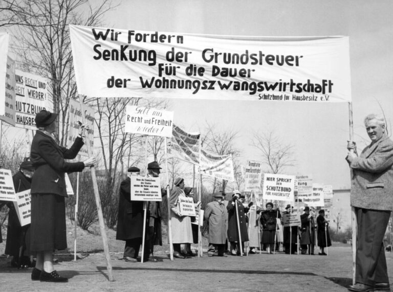 Hausbesitzer fordern bei einer Demonstration am 25.04.1958 vor dem Amtsgebäude des Senators für Bau- und Wohnungswesen am Fehrbelliner Platz in Berlin auf einem Spruchband die Senkung der Grundsteuer für die Dauer der Wohnungszwangswirtschaft. Initiator der Protestveranstaltung ist der Schutzbund für Hausbesitz e.V. Foto: Günter Bratke +++(c) dpa - Report+++ [dpabilderarchiv]