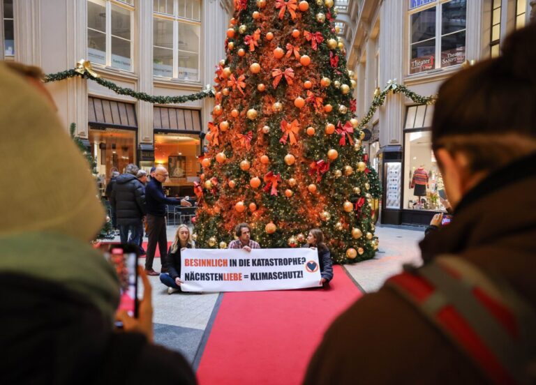 Die „Letzte Generation“ posiert vor einem verunstalteten Weihnachtsbaum, der im Leipziger Stadtzentrum steht.