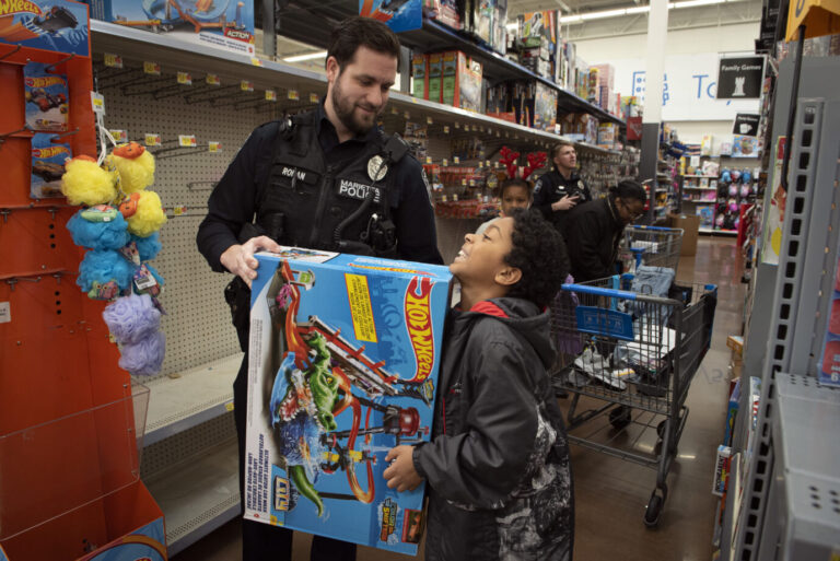 14. Dezember 2021, Marietta, Georgia, USA: Ein Polizeibeamter aus Marietta begleitet einen kleinen Jungen während eines "Shop With a Cop" für Kinder aus finanziell schwachen Familien durch den Laden. 50 Schüler aus der Stadt durften in Begleitung von Beamten und Detektiven des Marietta Police Department in einem örtlichen Walmart einkaufen, finanziert durch Unternehmen der Gemeinde und private Spenden. (Bildnachweis: © Robin Rayne/ZUMA) In Kalifornien werden geschlechterspezifische Spielzeugabteilungen nun verboten.