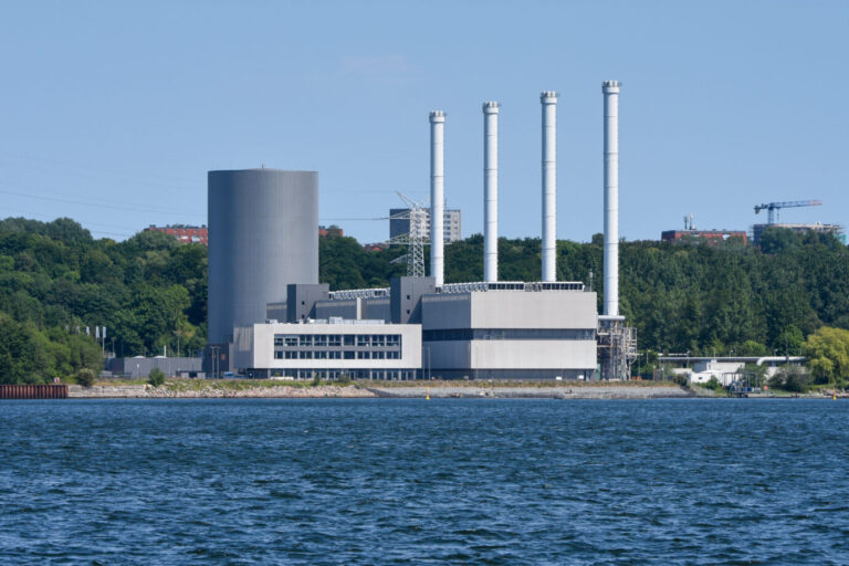 Kiel, Das Küstenkraftwerk der Stadtwerke Kiel AG am Ostufer der Kieler Förde in Hasselfelde ist ein in Kraft-Wärme-Kopplung betriebenes, modular aufgebautes Gasmotoren-Heizkraftwerk. Es verfügt über 20 Gasmotoren, die individuell regelbar sind und bringt insgesamt eine Leistung von ca. 191 Megawatt elektrisch und ca. 200 Megawatt thermisch. Rund 70.000 Kunden werden vom Kraftwerk mit elektrischer Energie und / oder mit Fernwärme beliefert. Links im Bild der große Fernwärmespeicher (grau), davor das Leitstellengebäude und rechts die vier 72 Meter hohen Schornsteine an den Blöcken für die Gasmotoren. Energiewende klappt nicht.