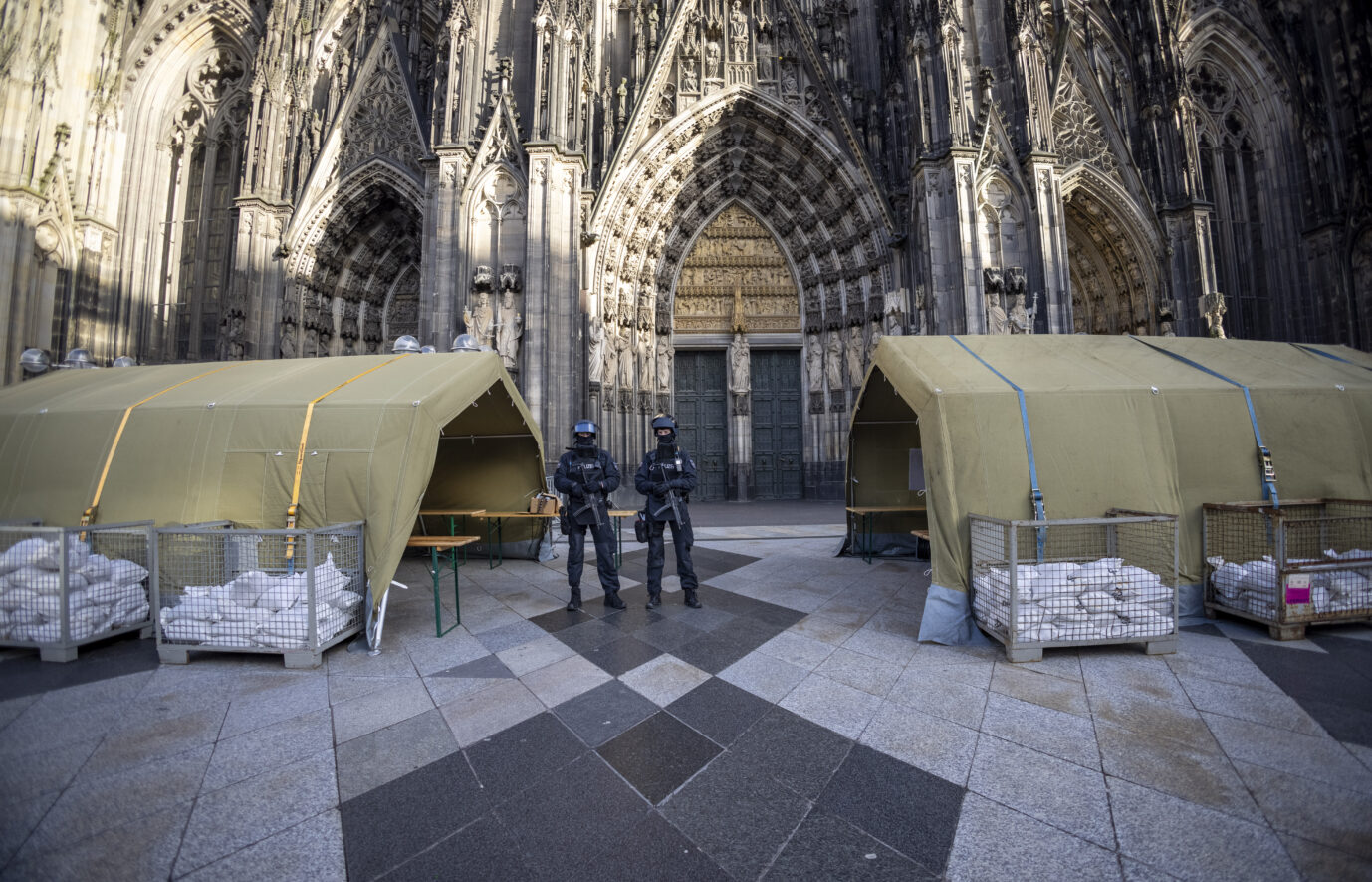 Schwerbewaffnete Polizisten und Sperren schützen den Kölner Dom am Silvestertag.