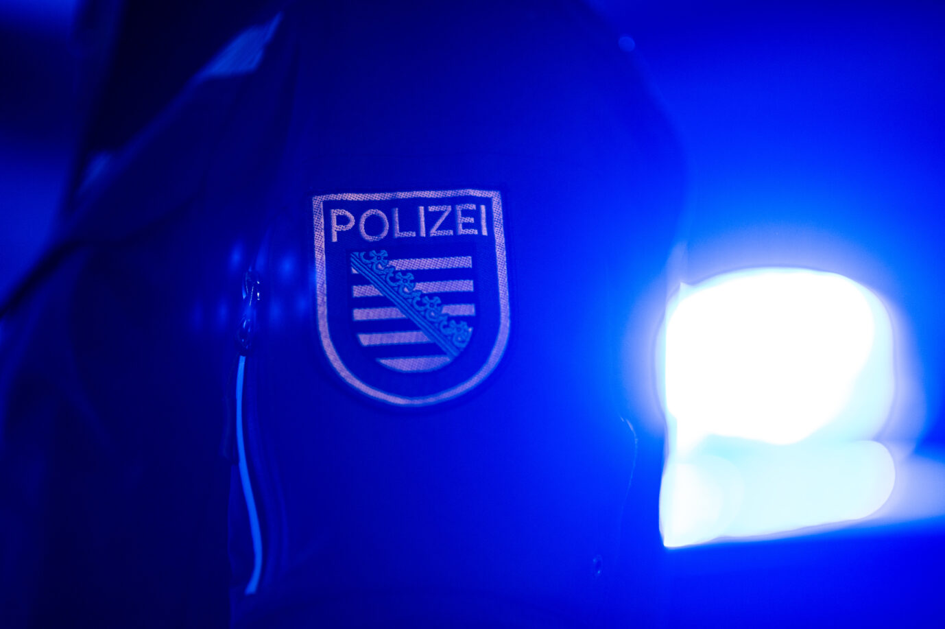 Ein Polizist steht neben einem Polizeiauto. In Chemnitz eskaliert die Migrantengewalt.