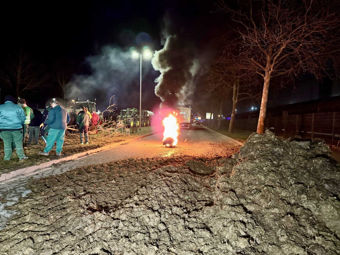 Landwirte blockieren mit Mist und brennenden Reifen eine Straße bei Magdeburg