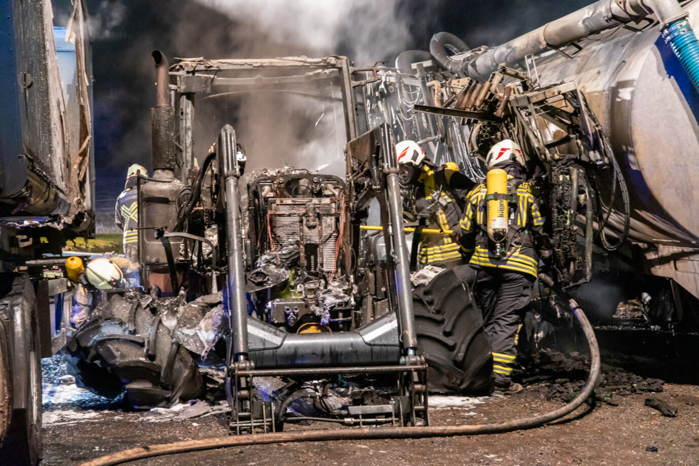 Feuerwehrleute bekämpfen die Flammen auf dem Hof in Oelsnitz. Vier Fahrzeuge der Bauern brennen aus.