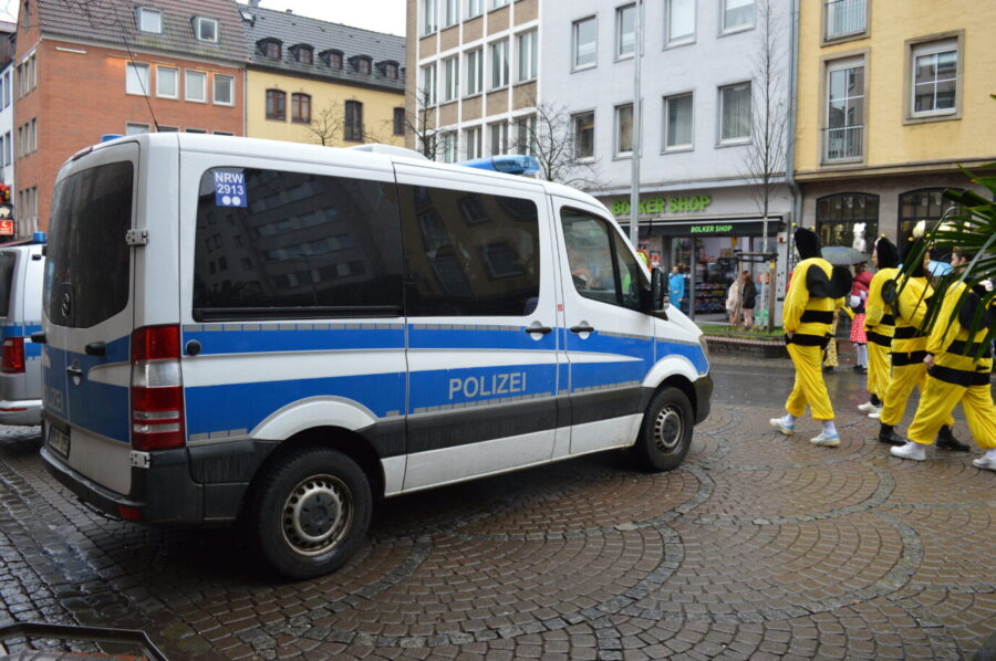 Karnevalisten laufen an einem Polizeiwagen in der Düsseldorfer Innenstadt vorbei: Die Beamten sind in der gesamten Altstadt verteilt Foto: JF