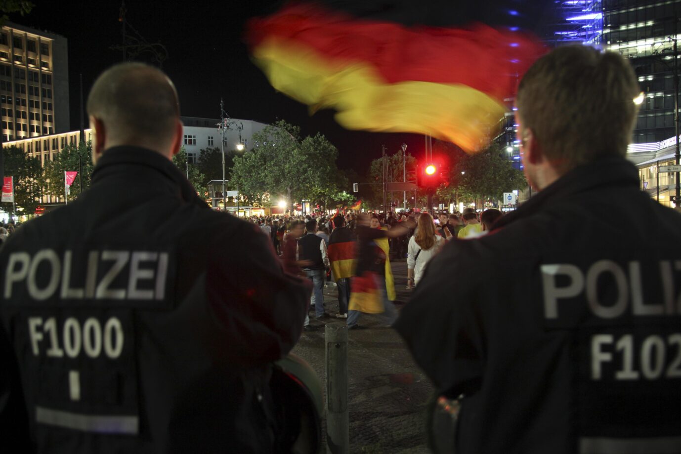 Deutschlandfahne: Polizisten beobachten deutsche Fußballfans. Selbst werden sie die Farben allerdings nicht in jedem Bundesland tragen dürfen