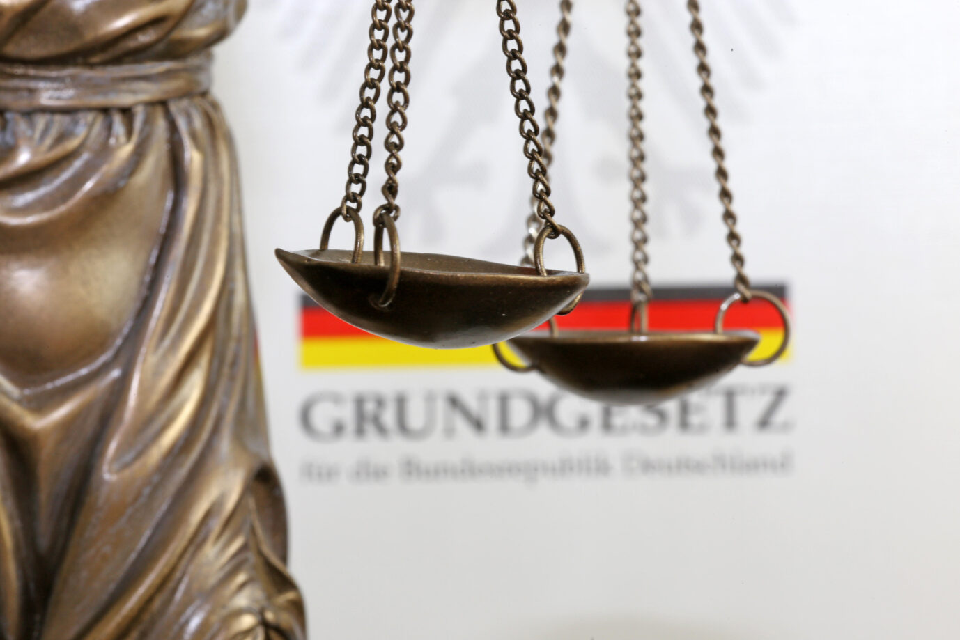 Nahaufnahme einer Justitia vor dem deutschen Grundgesetzbuch. Auch die AfD hat in diesem Land Grundrechte