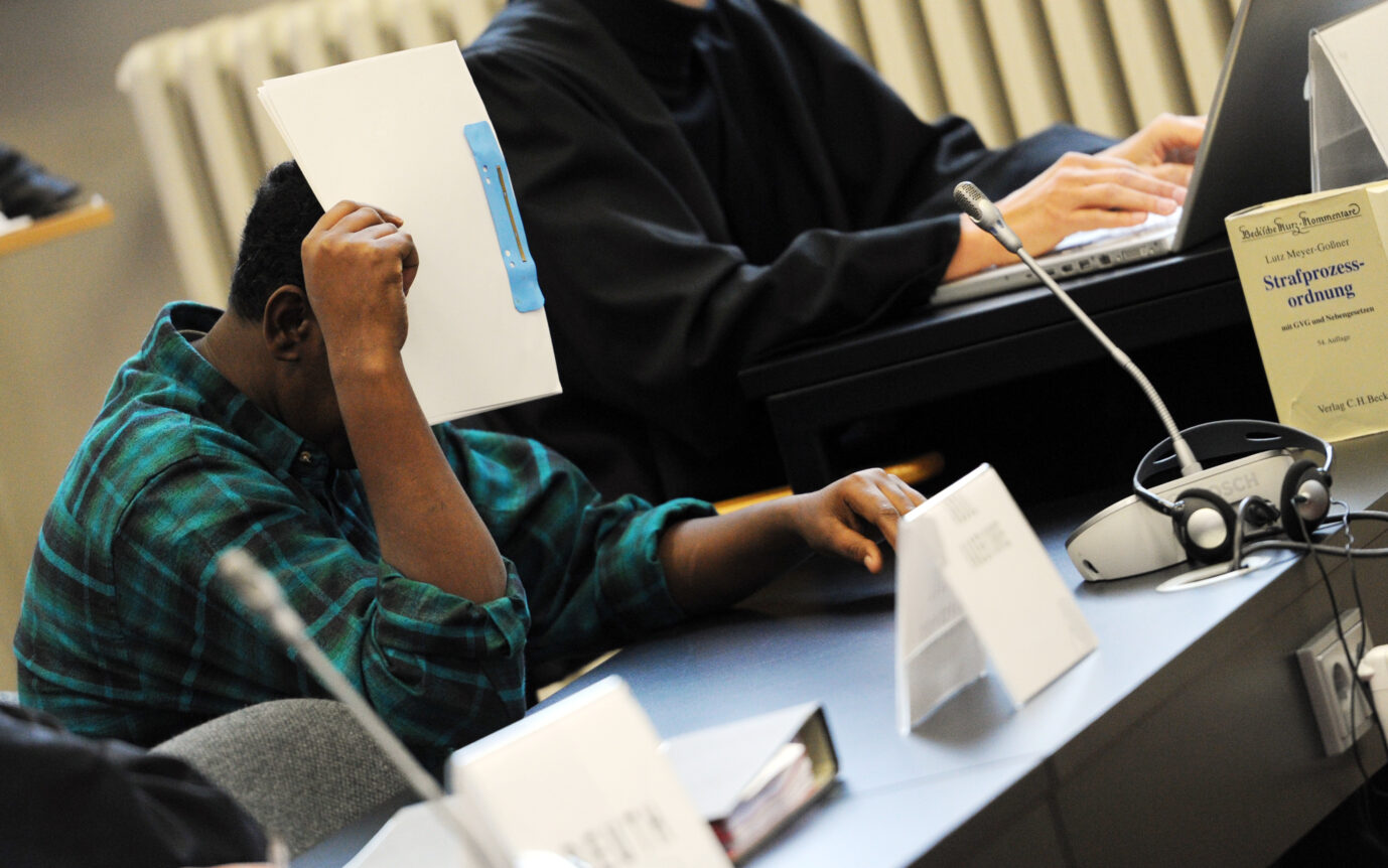 Ein mutmaßlicher Pirat aus Somalia sitzt am 15.10.2012 im Landgericht in Hamburg und verbirgt sein Gesicht hinter Akten. Der Piraten-Prozess gegen zehn Männer wurde mit einem letzten Wort der Angeklagten fortgesetzt. Foto: Daniel Reinhardt/dpa ++ Zwei der Somalier halten sich weiterhin in der Stadt auf.