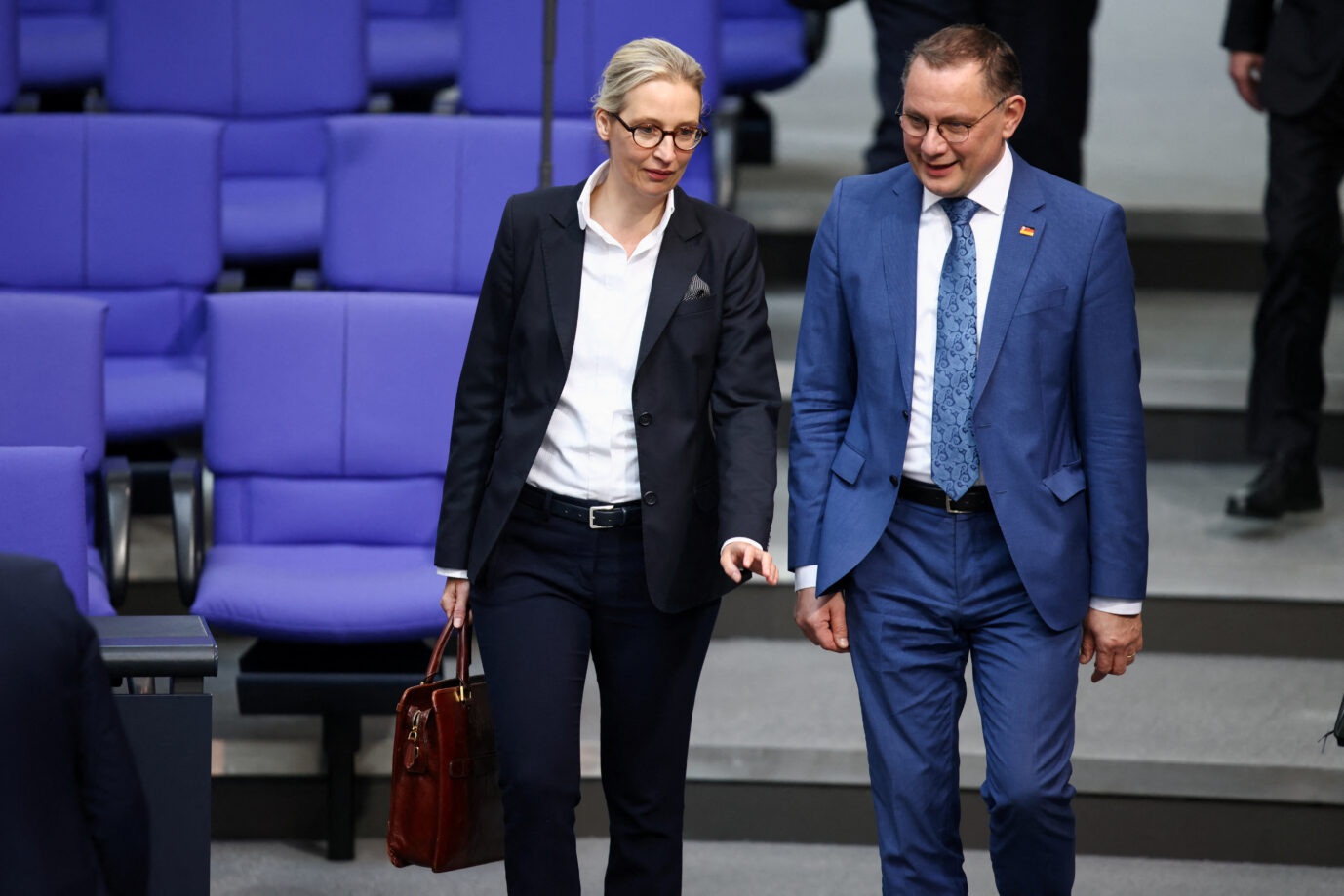 Die AfD-Vorsitzenden Alice Weidel und Tino Chrupalla laufen im Rednersaal des Bundestag umher und lächeln
