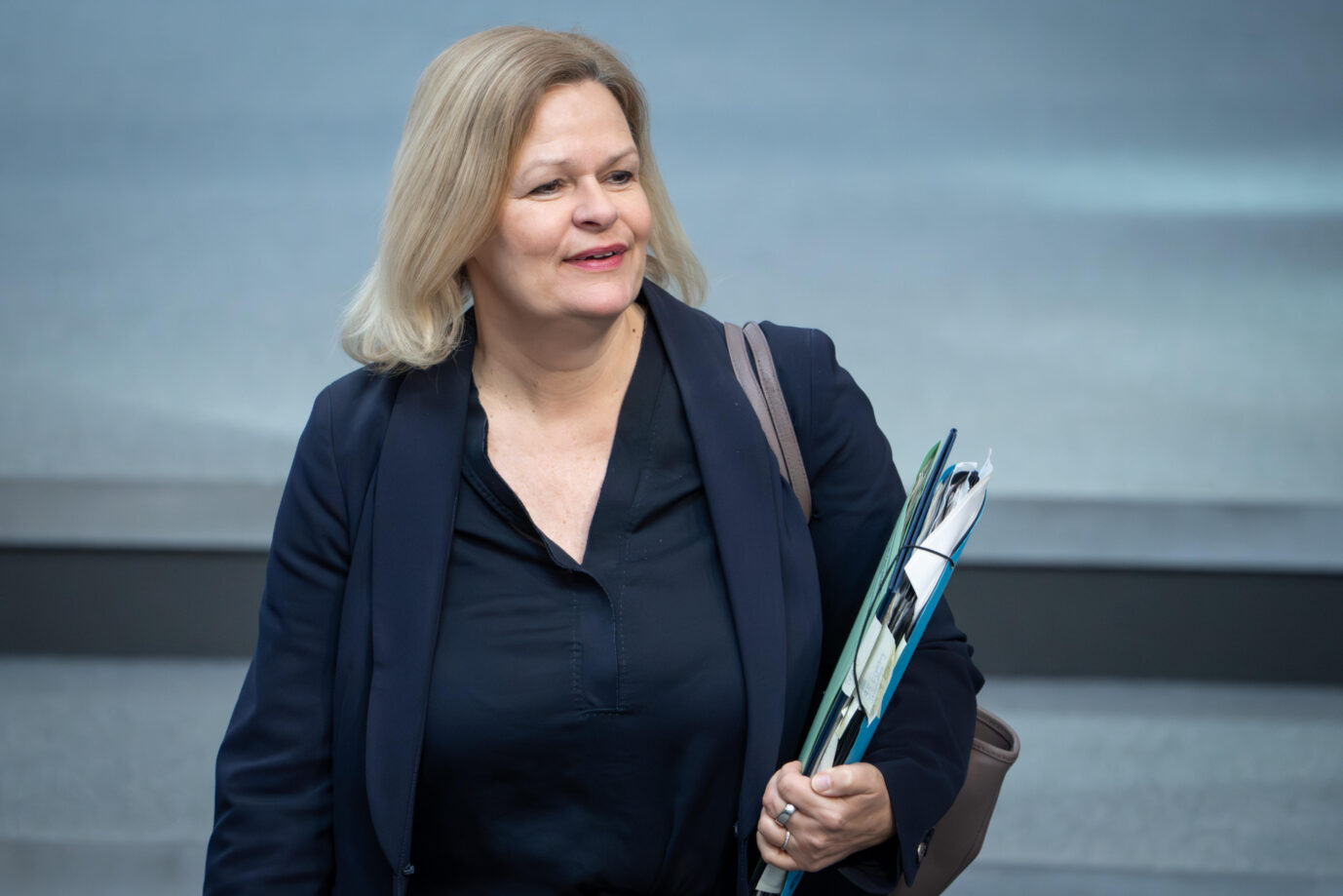 Innenminsterin Nancy Faeser (SPD) steht aufrecht und hält einen Ordner mit Dokumenten in ihrem linken Arm. Sie möchte mehr Diversität in öffentlichen Ämtern durchsetzen.
