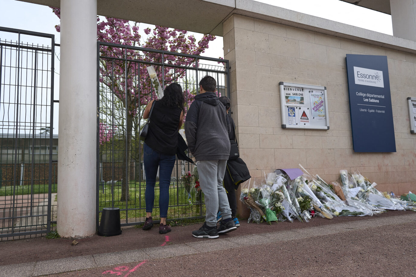 Zwei Kinder und eine Frau legen Blumen an der Schule in Viry-Chatillon. Einige Tage zuvor hatten dort Jugendliche einen Schüler getötet.