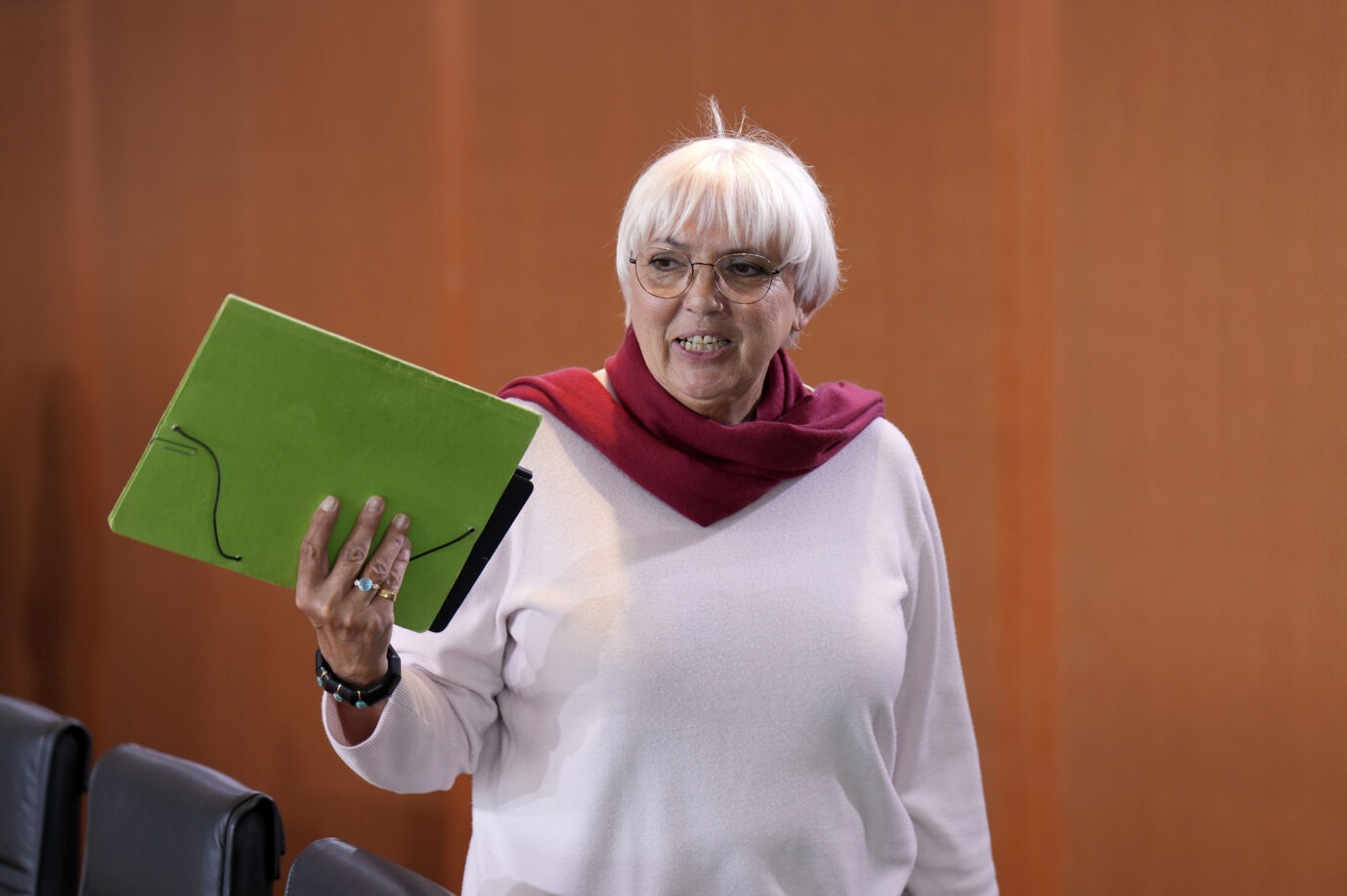 Grünen-Politikerin Claudia Roth schaut aggressiv an der Kamera vorbei und hält eine grüne Mappe in der rechten Hand. Sie haßt alle Deutschen und entfernte sie vor kurzem auch sprachlich aus dem Namen eines Vertriebenenverbandes