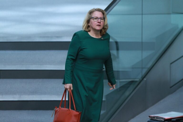 Entwicklungsministerin Svenja Schulze (SPD) trägt ein türkises Kleid und eine rotbraune Ledertasche und läuft eine Treppe hinunter. Ihr Gesichtsausdruck wirkt verblüfft, der Mund steht offen. Schulze fordert die Aufhebung der Schuldenbremse – um mehr Geld in die Entwicklungshilfe stecken zu können