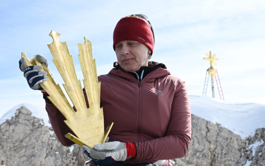 Die Kunstschmiedin Andrea Würzinger hält restaurierten Zacken des Gifpelkreuzes auf der Zugspitze in der Hand Foto: picture alliance/dpa | Angelika Warmuth
