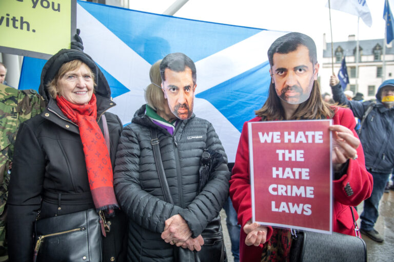 Auf dem Foto befinden sich Personen, die gegen das Inkrafttreten der Haßrede-Gesetzesnovelle in Schottland sind. Sie tragen Masken mit den Gesichtern des schottischen Ministerpräsidenten Humza Yousaf und dem Plakat mit der Überschrift "Wir hassen die Haßverbrechen-Gesetze."