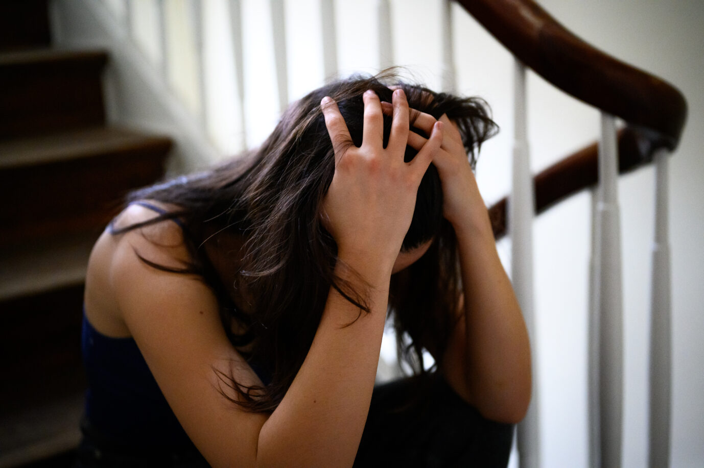 Auf dem Foto zeigt sich eine erwachsene Frau verzweifelt und hält ihren Kopf, während sie auf der Treppe sitzt. Dies soll die Hilflosigkeit der Frauen gegenüber Tätern symbolisieren. Vergangenes Jahr vermeldete die Berliner Polizei 111 Gruppenvergewaltigungen. (Symbolbild)