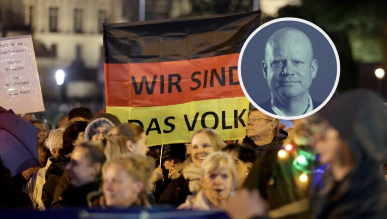 Demonstranten halten eine Deutschlandfahne mit der Aufschrift "Wir sind das Volk" hoch, Grundgesetz