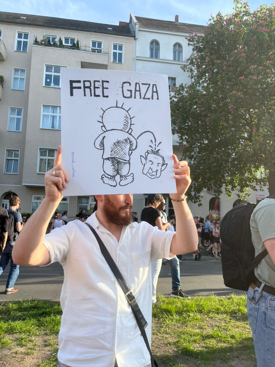 Ein Demo-Teilnehmer hält ein anti-israelisches Schild in die Höhe