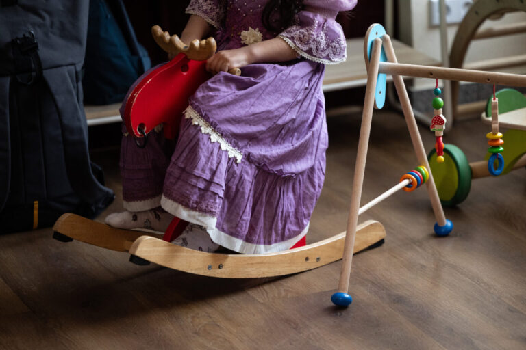 Mutterschaft: Ein Kind, gekleidet in ein violettes Kleid, sitzt auf einem Schaukelpferd (Symbolbild)