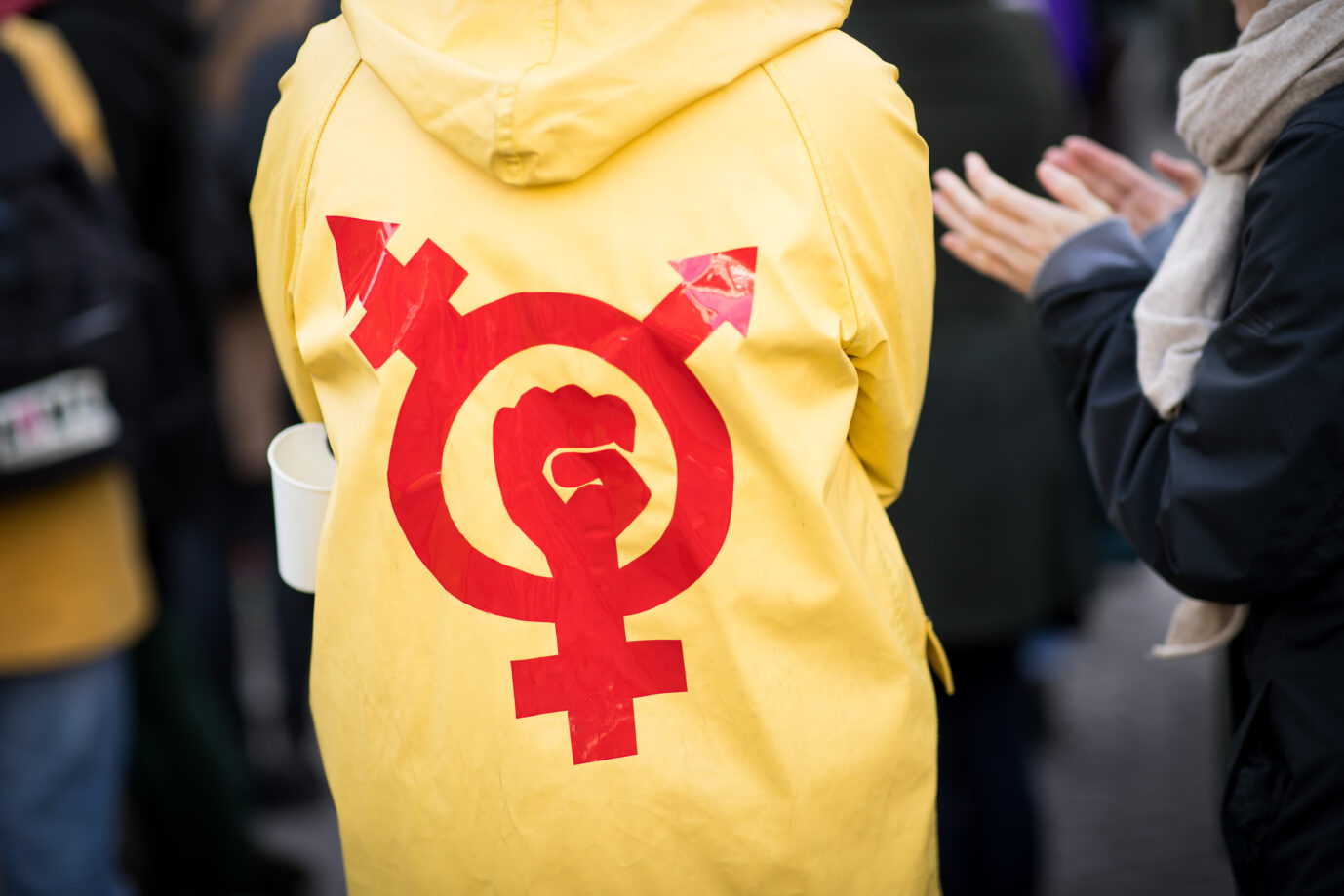 08 March 2019, Hamburg: A woman wears a yellow raincoat with a gender and protest symbol at a rally for International Women's Day in front of the City Hall. Parties, unions, and women's rights organizations have called for a rally for more equality in front of the Hamburg City Hall on World Women's Day. Photo: Christian Charisius/dpa