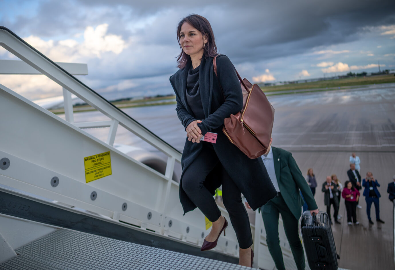 Außenministerin Annalena Baerbock (Grüne) betritt die Zugangsrampe eines Flugzeugs und grinst