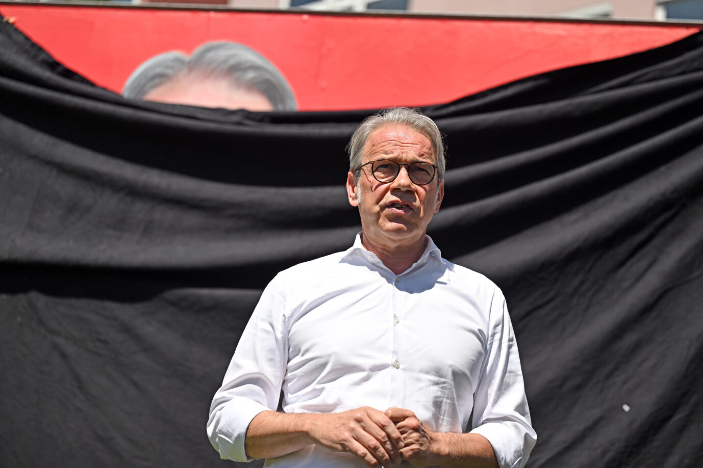 Der thüringische Innenminister Georg Maier (SPD) spricht vor einer schwarzen Flagge, die ein SPD-Wahlplakat verhüllt. Wenn es nach ihm geht, soll der schwerkriminelle marokkanische Asylbewerber bald nun endlich abgeschoben werden