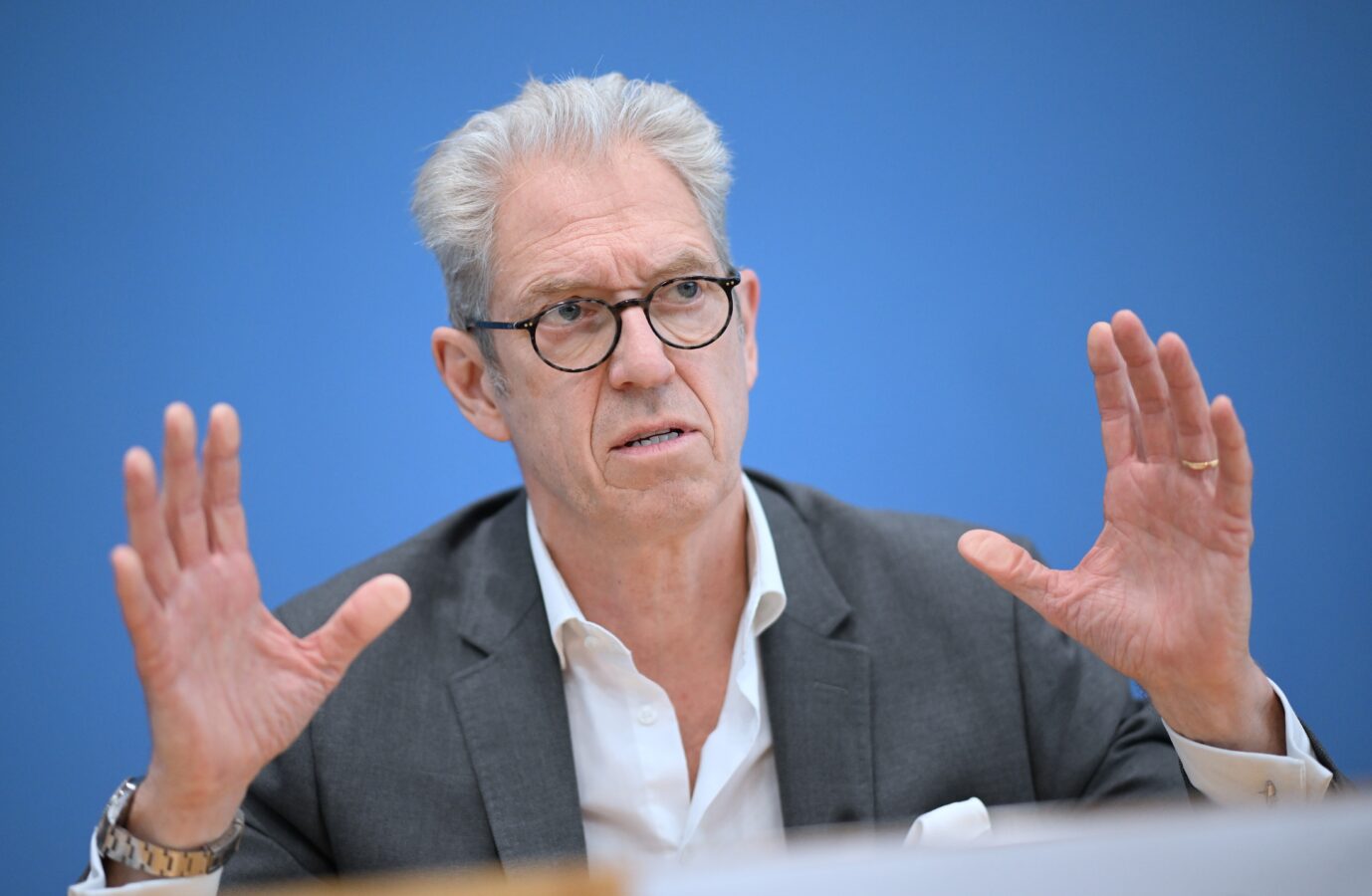 Der Vorstandsvorsitzende der Kassenärztlichen Bundesvereinigung gestikuliert auf einer Pressekonferenz mit seinen Händen und schaut besorgt