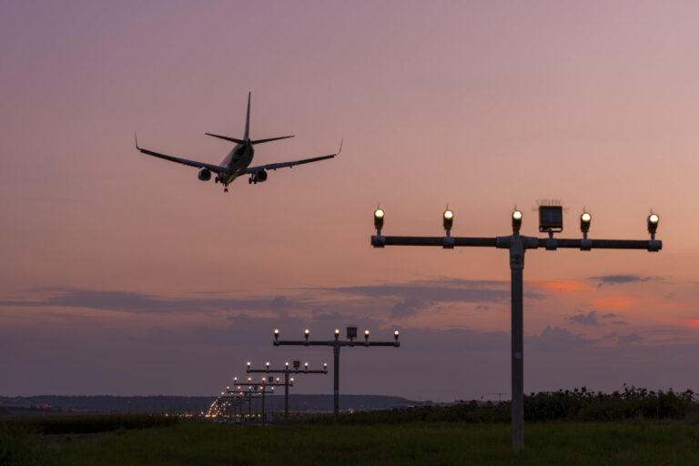 Ein Passagierflugzeug fliegt in der Abenddämmerung – oder im Morgenrot – über eine Landebahn. Vielleicht transportiert es gerade ein paar afghanische Straftäter zurück nach Afghanistan