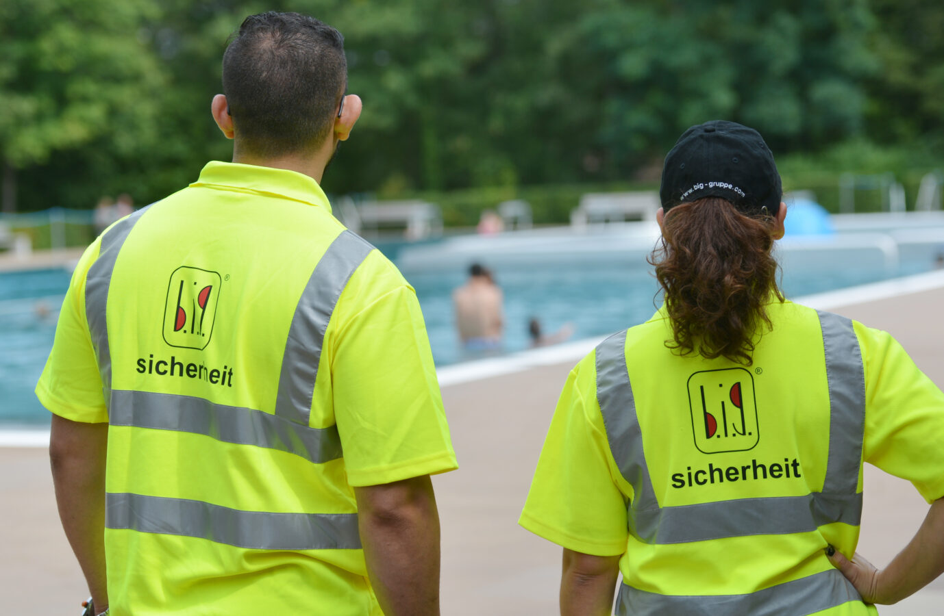 Zwei Mitarbeiter eines Sicherheitsdienstes beobachten am 18.08.2016 in Stuttgart (Baden-Württemberg) das Geschehen in einem Freibad. Foto: Franziska Kraufmann/dpa