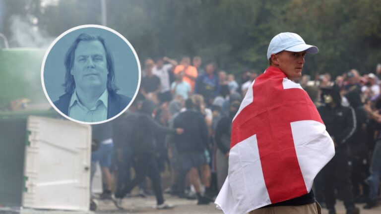 Auf dem Foto steht ein mit englischer Fahne umhüllter Demonstrant gegenüber einer Menschenmenge während der Ausschreitungen in Großbritannien. (Themenbild)