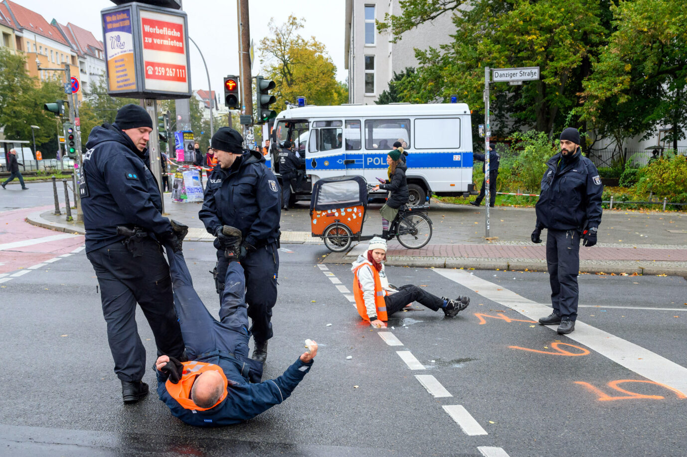 Tausende Gebührenbescheide stellt die Berliner Polizei an die „Letzte Generation“ aus. Unrechtmäßig, wie nun das Oberverwaltungsgericht in Berlin befindet. Die Klimakleber erwarten über Hunderttausende Euro an Rückzahlungen. Polizisten schleifen Aktivisten der Letzten Generation an den Füßen von der Straße. Er ruft immer wieder: "Ich bin ein Mensch!", die Polizisten antworten beide: "Ich bin auch ein Mensch." Bei Blockade der Prenzlauer Allee/Danziger Allee, Berlin, 20.10.2023 Die Berliner Polizei entfernt Klimakleber von der Straße: Die Räumung kann sie der „Letzten Generation“ nicht in Rechnung stellen Foto: picture alliance / PIC ONE | Stefan Müller