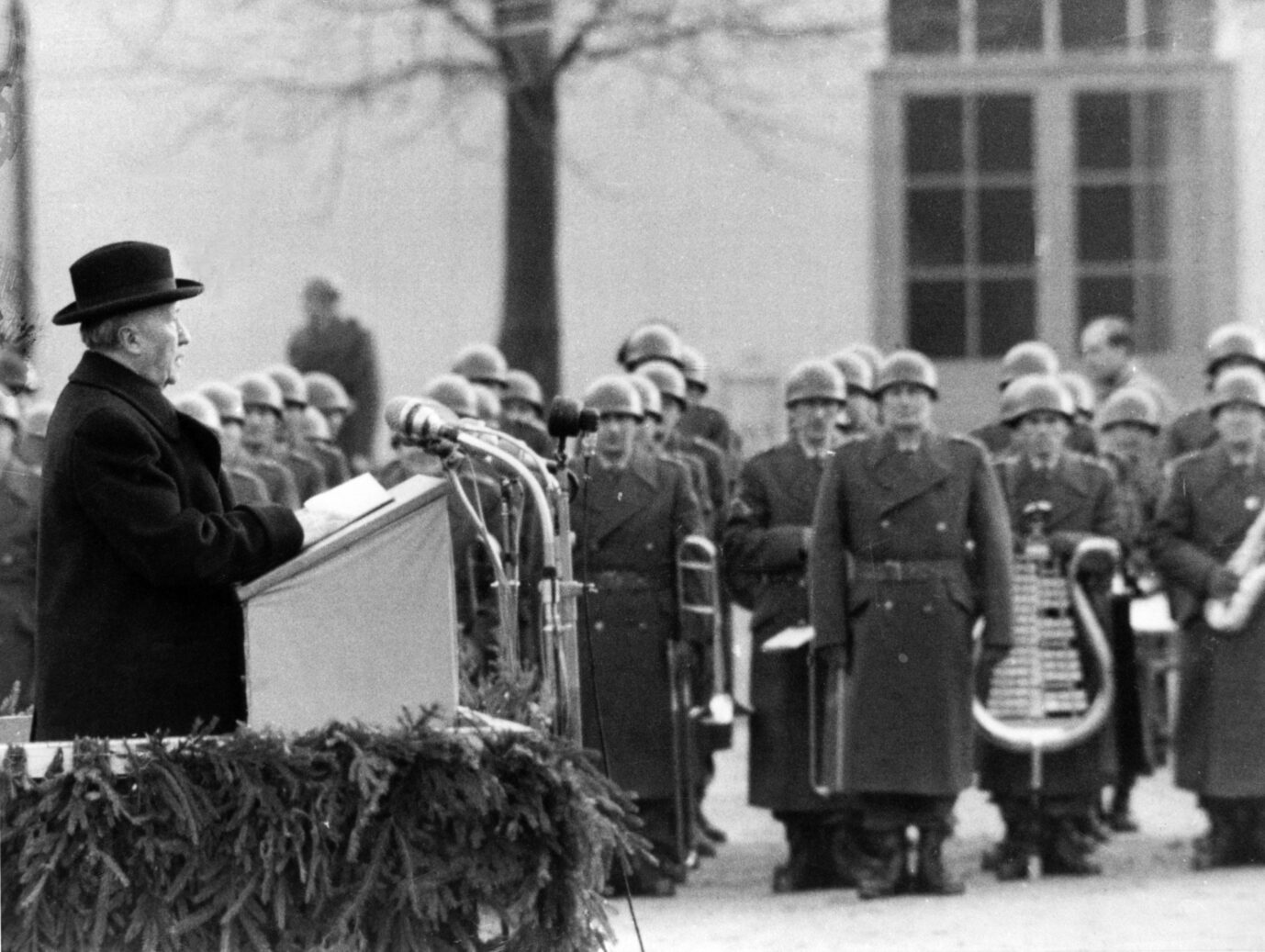 Der damalige Bundeskanzler Konrad Adenauer (CDU) steht an einem Rednerpult und spricht vor uniformierten Soldaten der gerade frisch gegründeten Bundeswehr