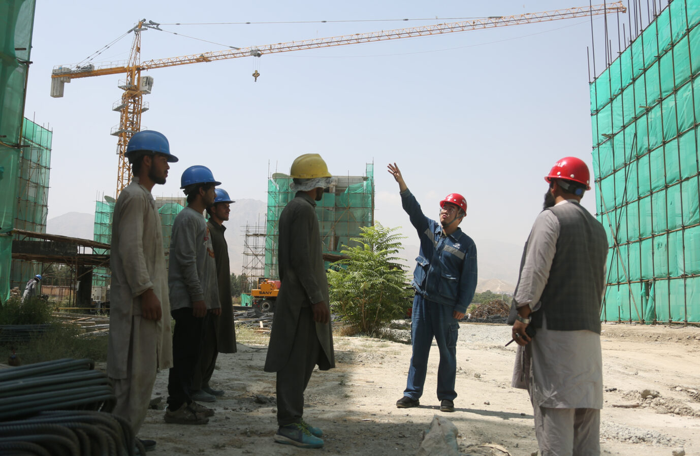 Ein Chinesischer Ingenieur und einheimische Bauarbeiter vor einem von der Pekinger Metallurgical Group finanzierten Wohngebäudekomplex in Afghanistans Hauptstadt Kabul Foto: picture alliance / Xinhua News Agency | Saifurahman Safi