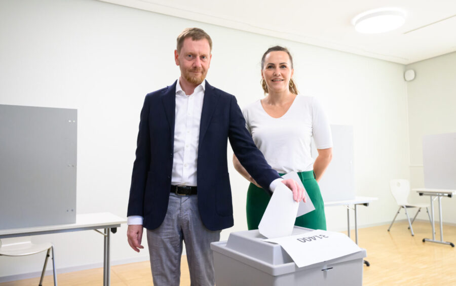 Michael Kretschmer (CDU), Ministerpräsident von Sachsen, steht mit seiner Frau Annett Hofmann bei der Stimmabgabe zur Landtagswahl in Sachsen im Wahllokal an einer Wahlurne. In Sachsen findet am Sonntag die Landtagswahl statt.Sachsens Ministerpräsident Michael Kretschmer (CDU) neben seiner Frau Annett Hofmann bei der Stimmabgabe Foto: picture alliance/dpa | Robert Michael