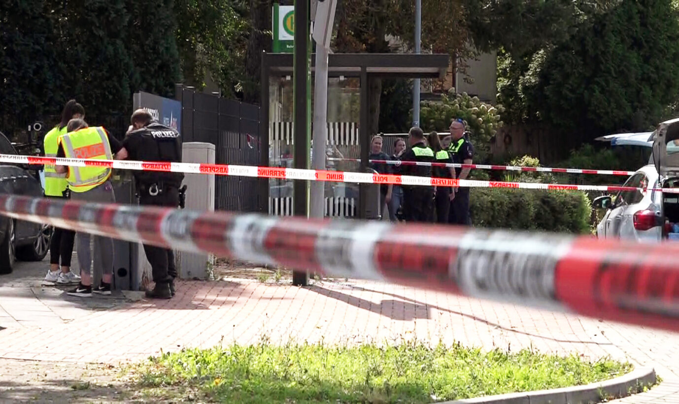 Polizisten stehen hinter Absperrband am Tatort im Bereich der Bahnhofstraße. Bei einer mutmaßlichen Stichwaffen-Attacke ist ein 61-Jähriger gestorben. Der Mann wurde gegen 10.00 Uhr so schwer verletzt, dass er kurze Zeit später starb, wie die Polizei mitteilte. Nun wurde ein Iraker festgenommen.