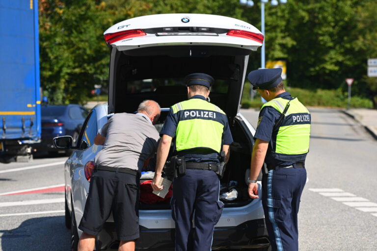 Grenzkontrolle in Bayern: Polizeibeamte in gelben Westen durchsuchen im bayerischen Burghausen den Kofferraum eines Autos