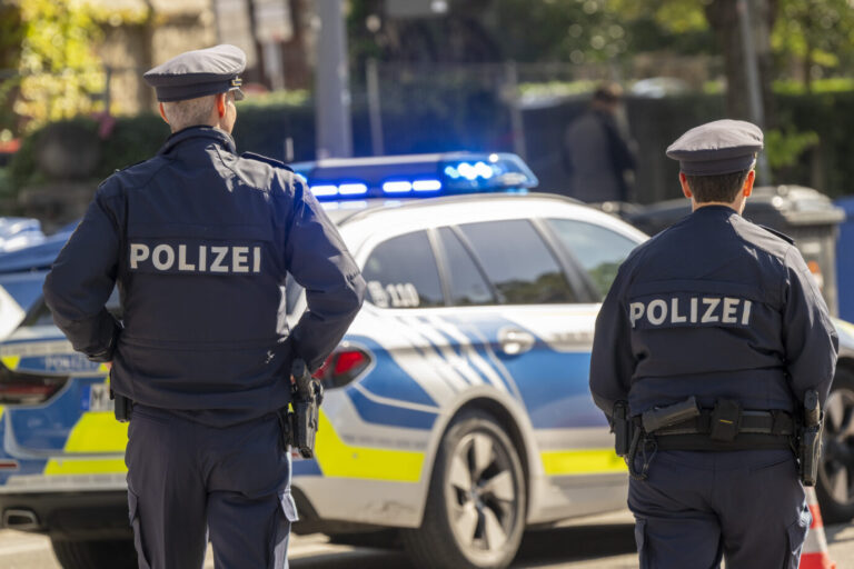 Uniformierte deutsche Polizisten stehen neben einem blauen Polizeiauto. Eventuell müssen sie gerade wegen der Messerattacke eines Minderjährigen in den Einsatz