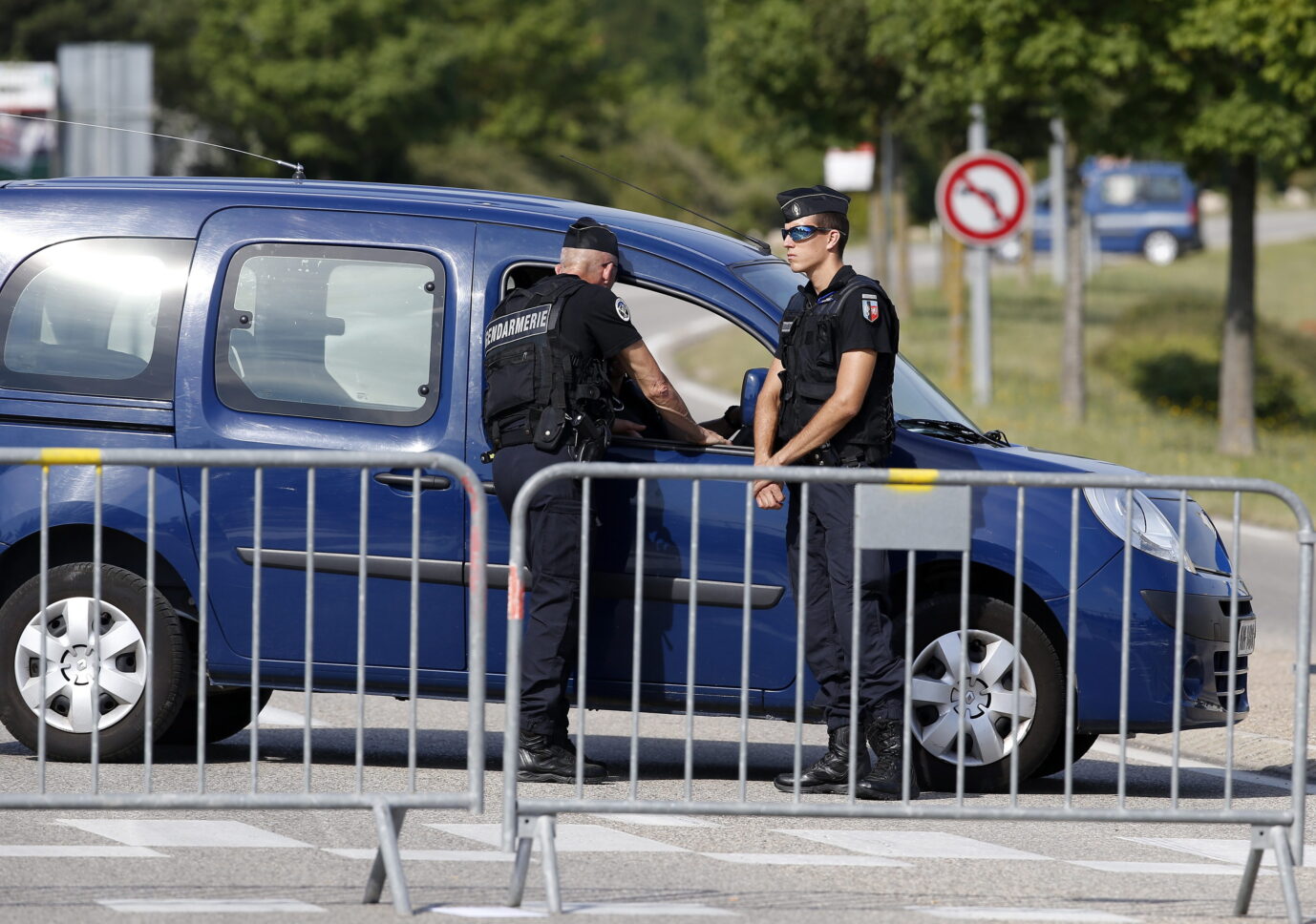 Zwei Männer in französischen Polizeiuniformen stehen vor einem Polizeiauto – möglicherweise ermitteln sie im Fall der ermordeten Studentin Philippine