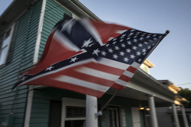 Eine Mischung aus Südstaaten- und Stars-and-Stripes-Flagge flattert an der Veranda eines typisch amerikanischen Holzhauses in Shawnee Ohio. Ein typischer Anblick einer Hillbilly-Gegend